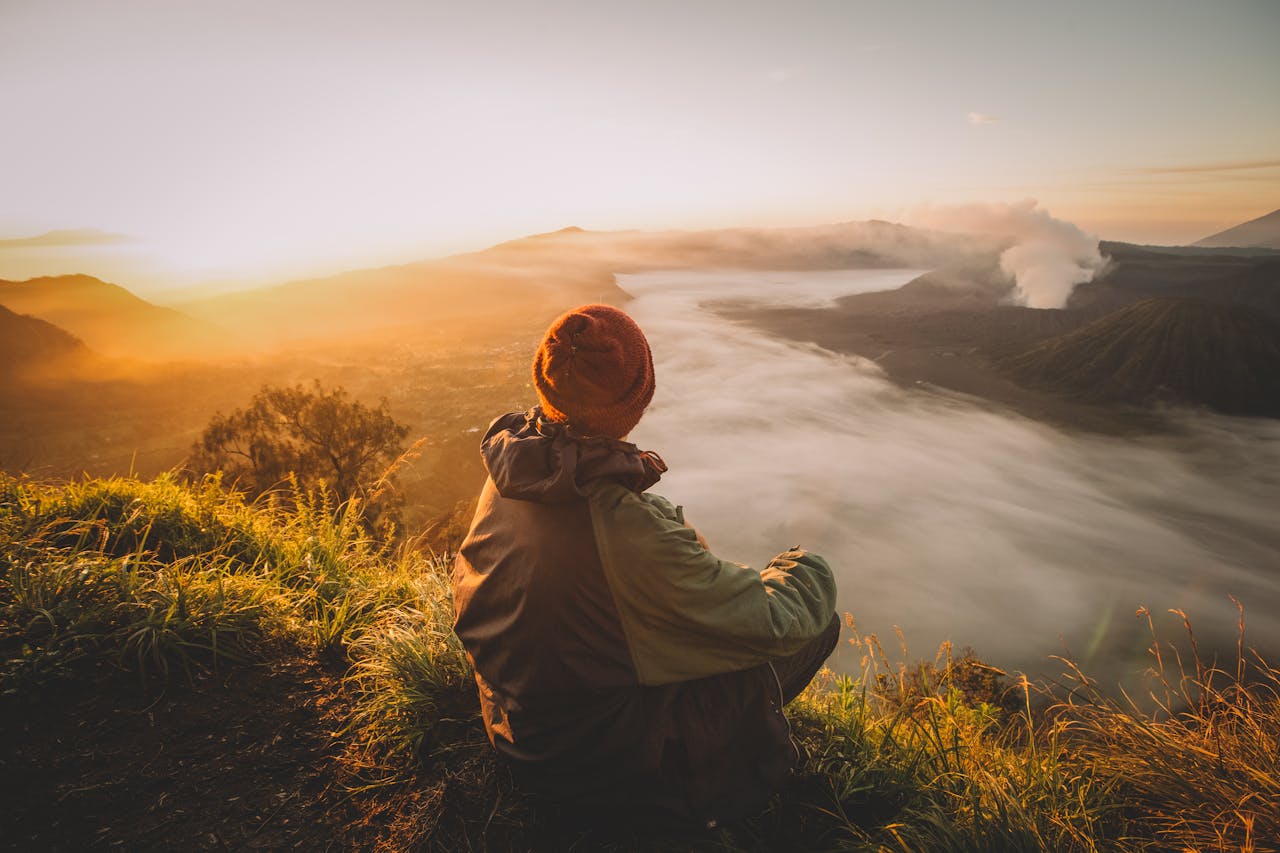 A person enjoys the sunrise view over a misty landscape in East Java, Indonesia.